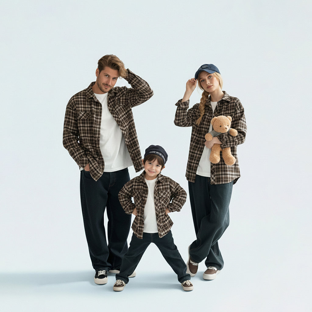 Full family in matching family outfits wearing brown plaid shirts for a coordinated autumn travel look.