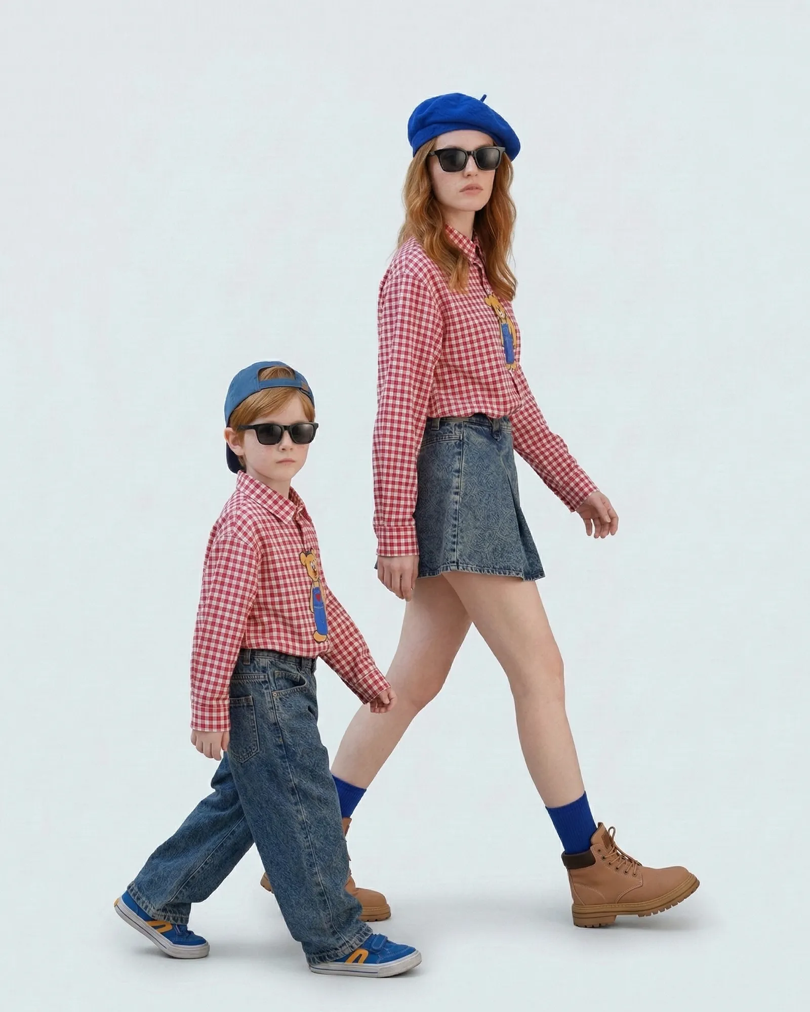 Mother and son walking in matching red and white plaid shirts for urban photoshoot scenario.
