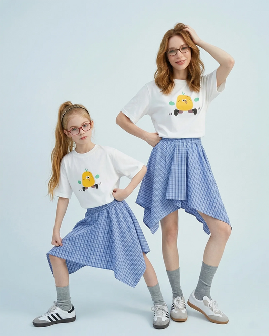 Mother and daughter in matching family outfits, wearing white graphic tees and blue plaid asymmetrical handkerchief-hem skirts.
