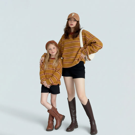 Mother and daughter in matching mommy and me outfits wearing oversized striped knit sweaters.